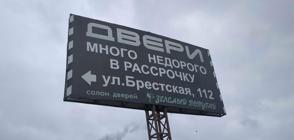 Монтаж баннера на билборд для салона дверей Зеленый попугай